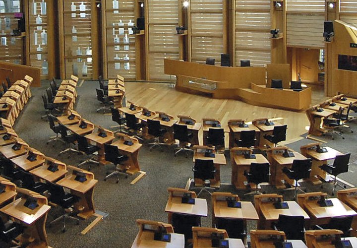 Conference room with numerous desks, dominated by wooden furniture and wooden panelling.