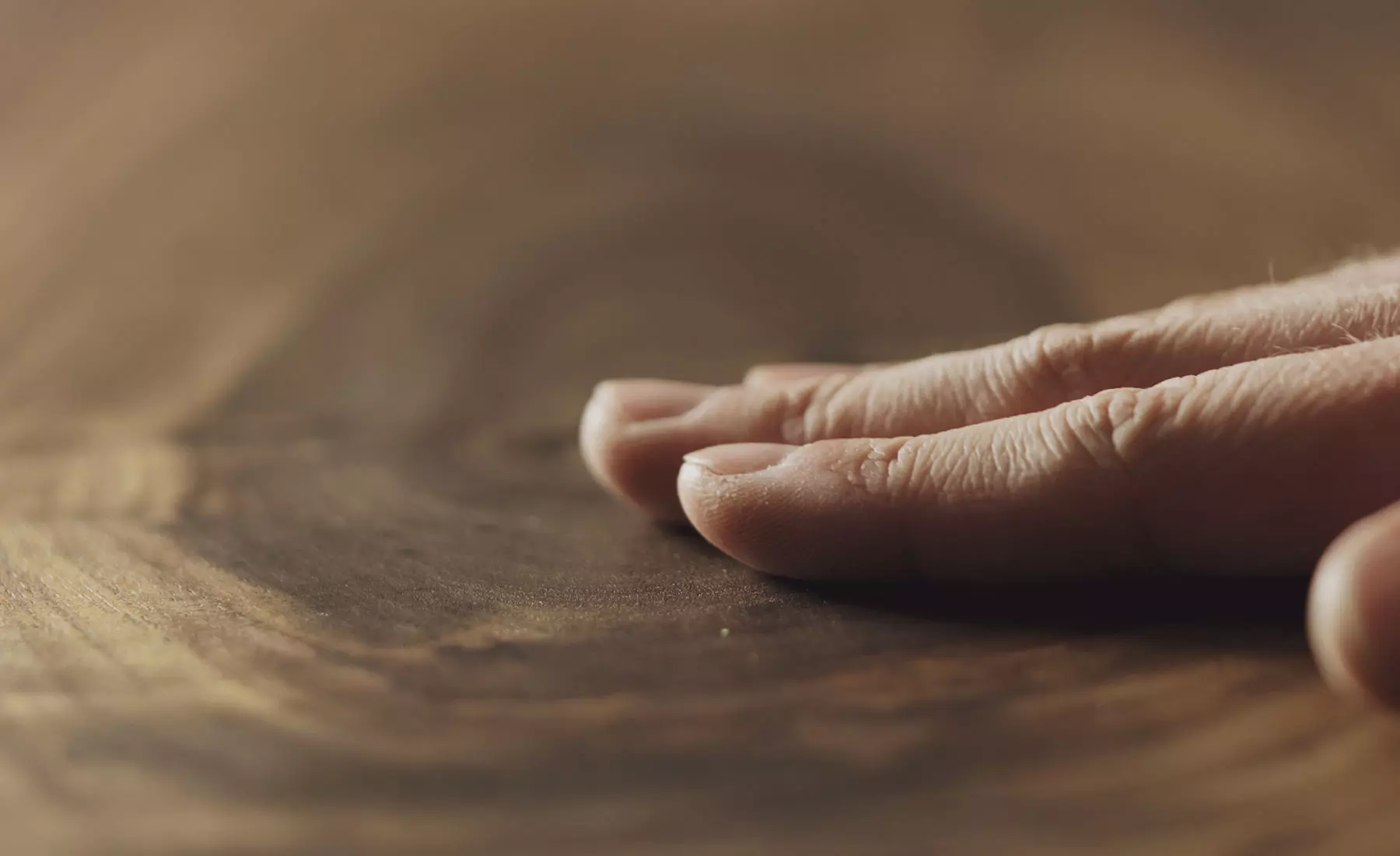 Une main caresse une planche de bois dur