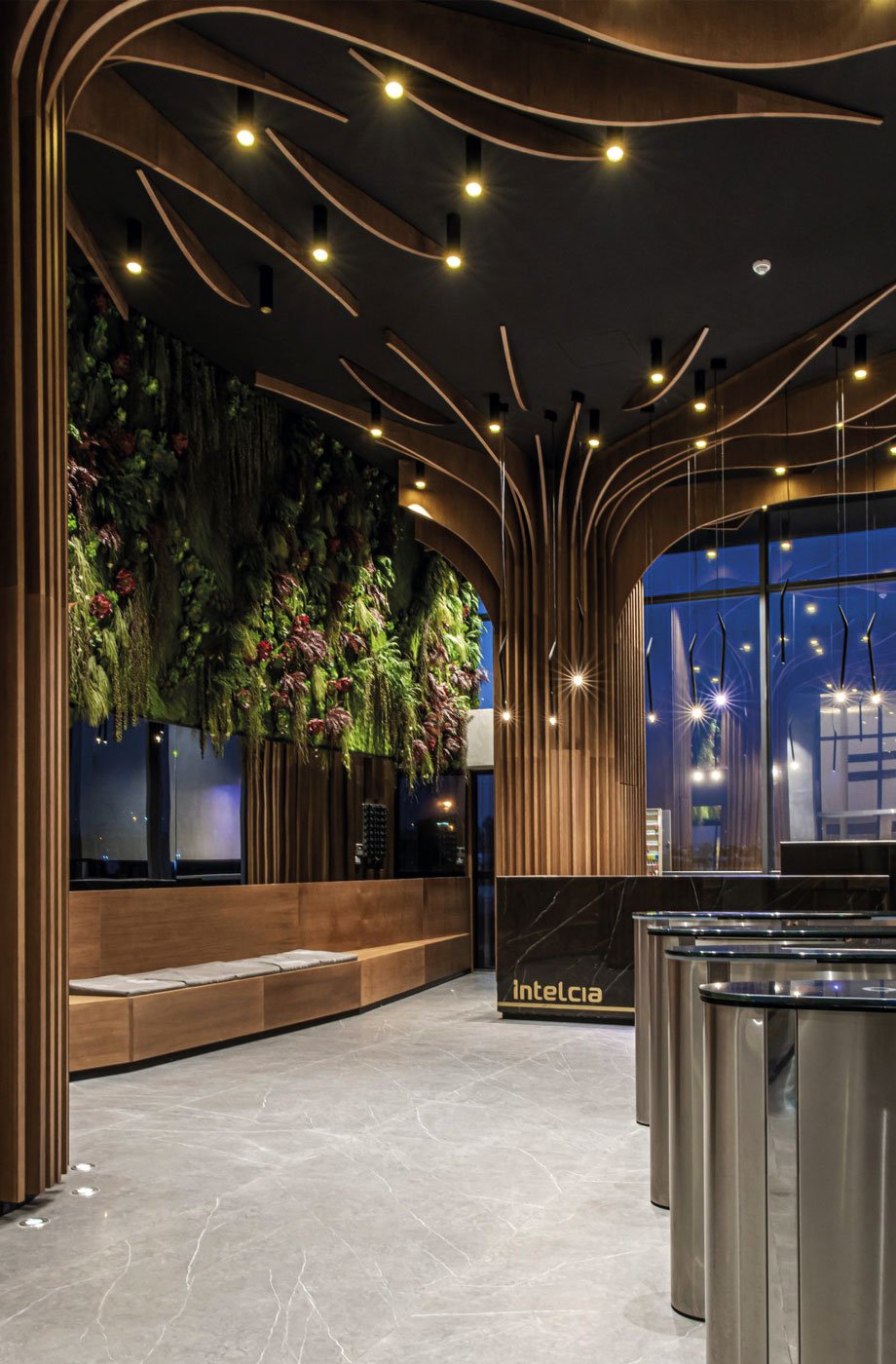 A company entrance hall featuring large columns covered with wooden planks that resemble trees reaching up to the ceiling.